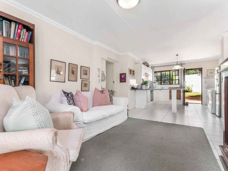 Open-plan living and kitchen area featuring tiled floors, neutral walls, and direct access to the rear garden.
