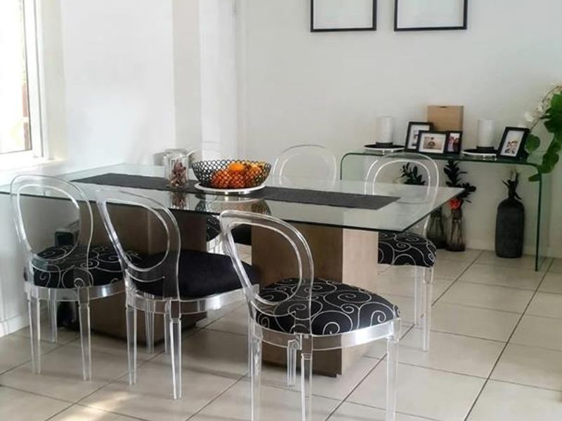 A bright dining area featuring neutral tiled flooring and a simple flush mount ceiling light, providing a clean and functional space for meals.