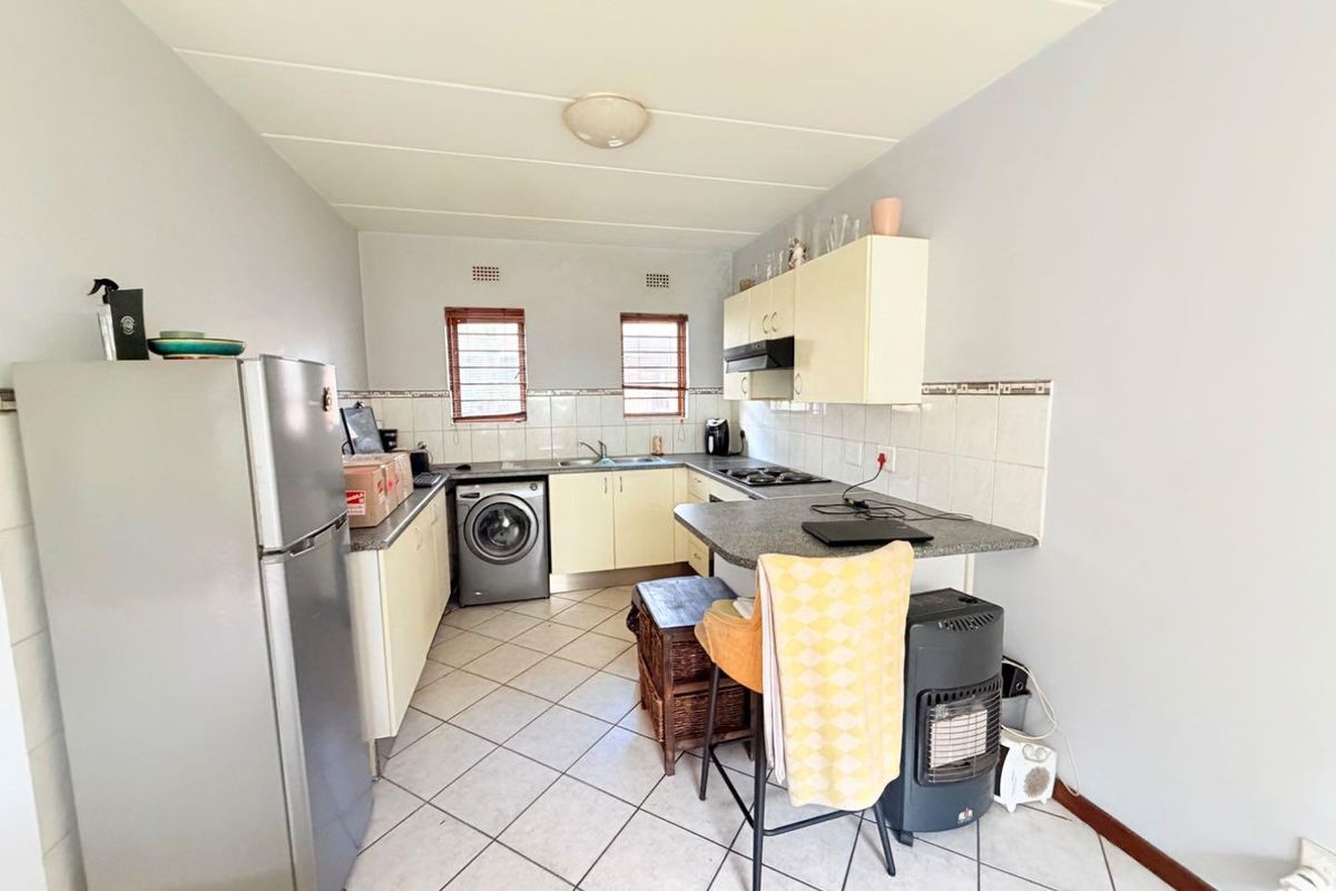A functional kitchen featuring built-in cabinetry, tiled backsplash, integrated hob with extractor fan, and tiled flooring.