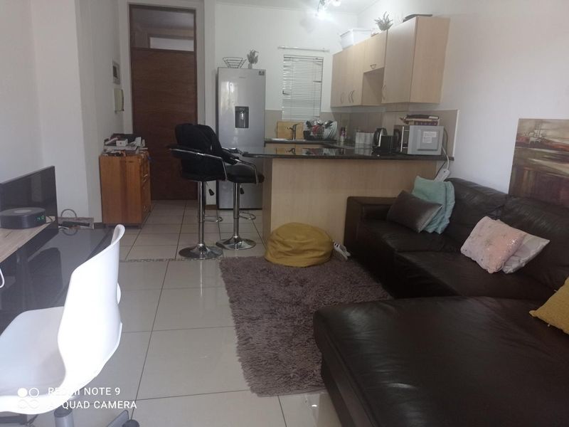 Open plan living area featuring a kitchen with granite countertops, breakfast bar, and tiled flooring throughout.