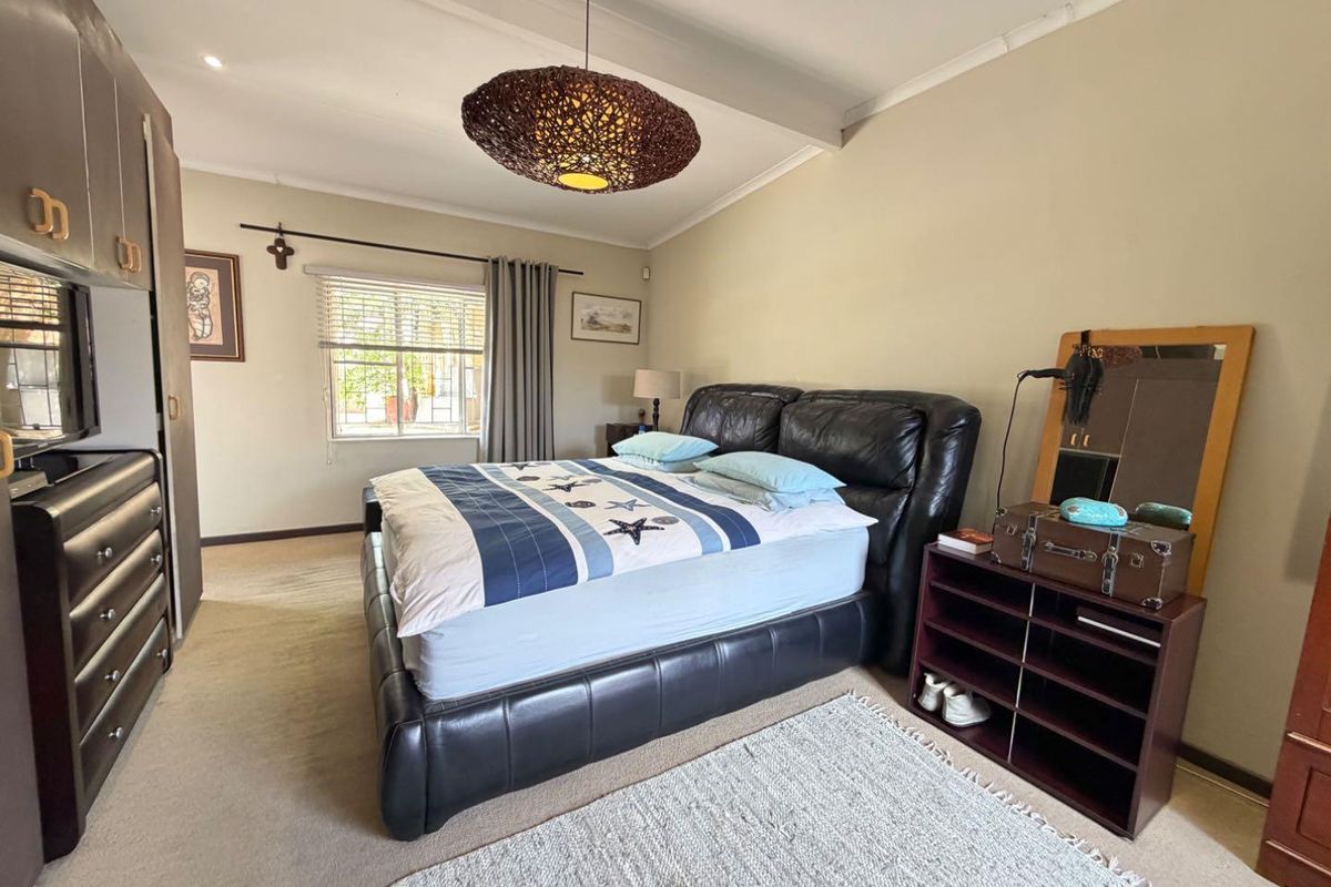 A bedroom featuring built-in cabinetry, carpeted flooring, and a window with fitted curtain rails.