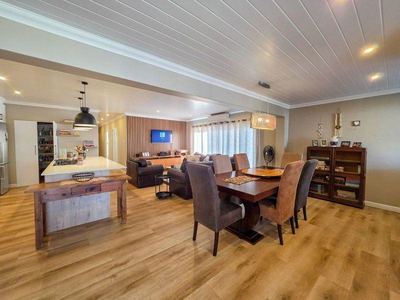 Spacious open-plan living, dining, and kitchen area featuring modern timber slat accents, light laminate flooring, and a functional kitchen island with integrated storage.