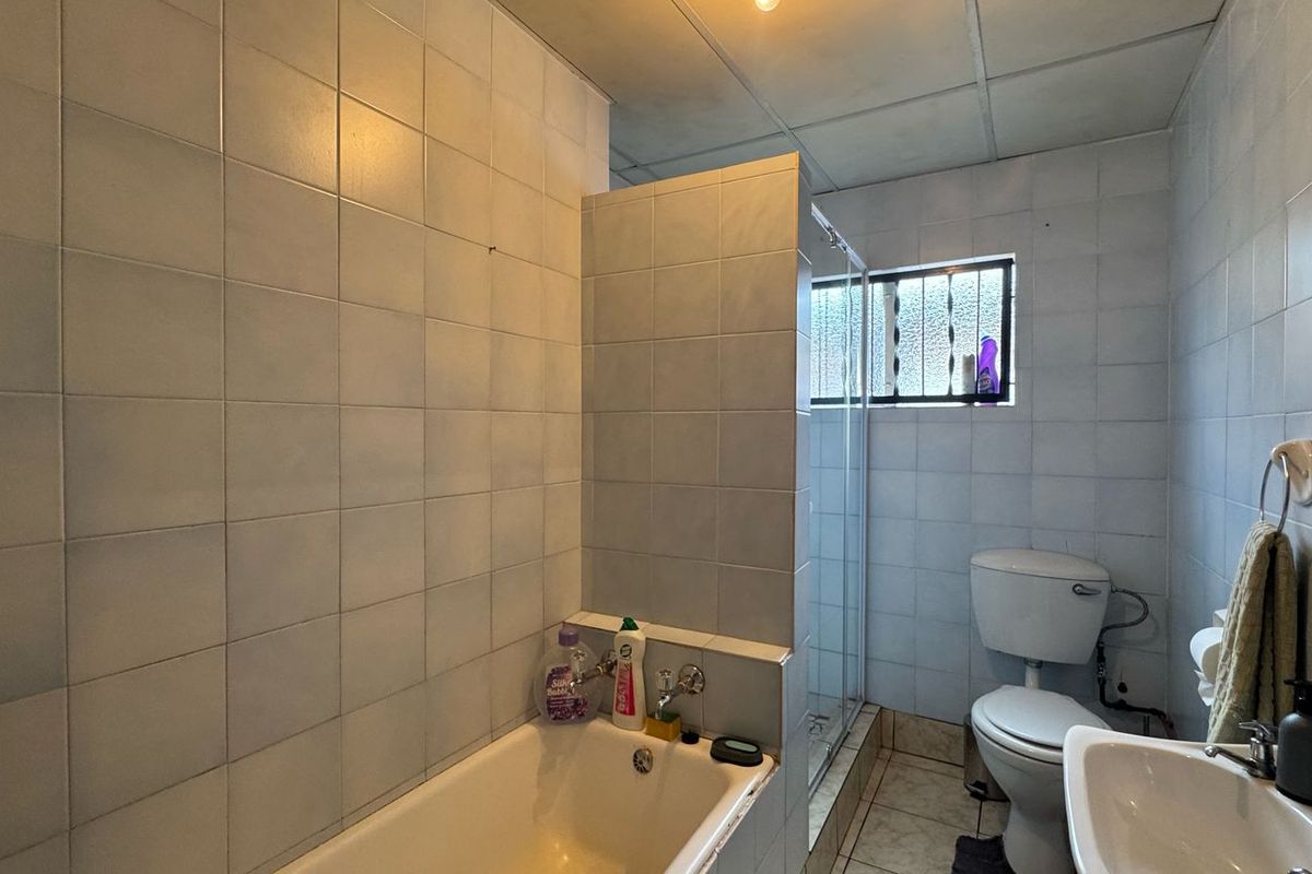 A functional bathroom featuring a bathtub, separate shower enclosure, toilet, and basin with tiled walls and flooring.
