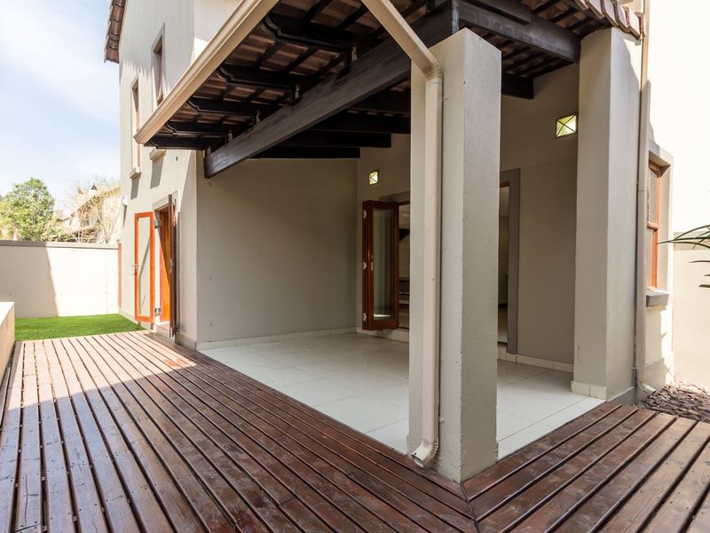 A covered patio area featuring timber decking, tiled flooring, and exposed timber beams, providing a seamless transition to the outdoor garden space.
