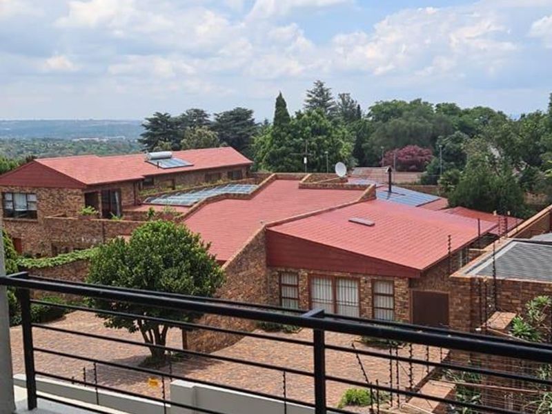 A covered balcony featuring a metal balustrade, offering an elevated view over the surrounding residential complex and neighborhood.