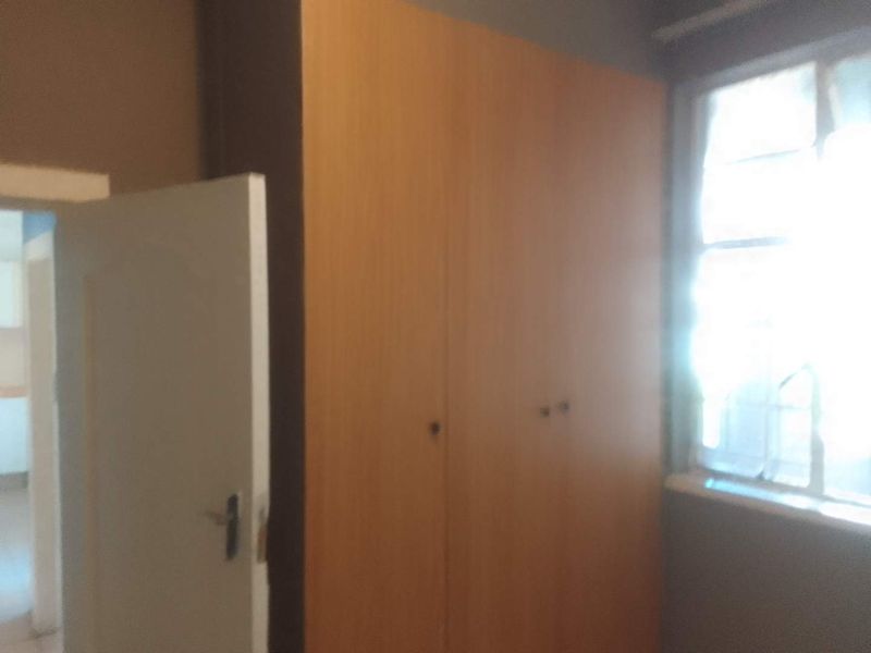 A bedroom featuring a built-in wooden wardrobe and natural light from the window.