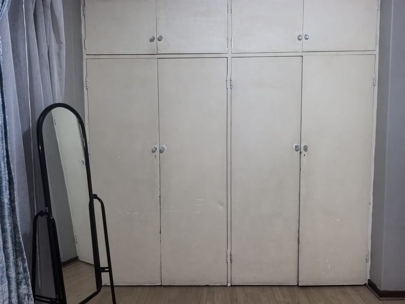 Bedroom featuring floor-to-ceiling built-in cupboards with laminate flooring.
