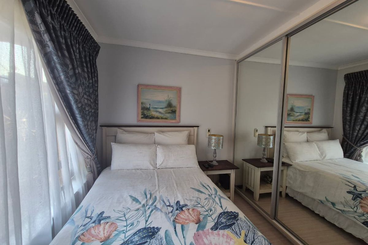 A well-maintained bedroom featuring laminate flooring, a large built-in mirrored wardrobe, and decorative cove cornicing.