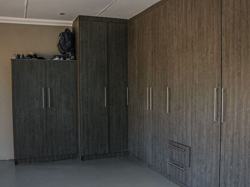 A bedroom featuring extensive dark wood-grain built-in cupboards providing ample storage space and neutral flooring.
