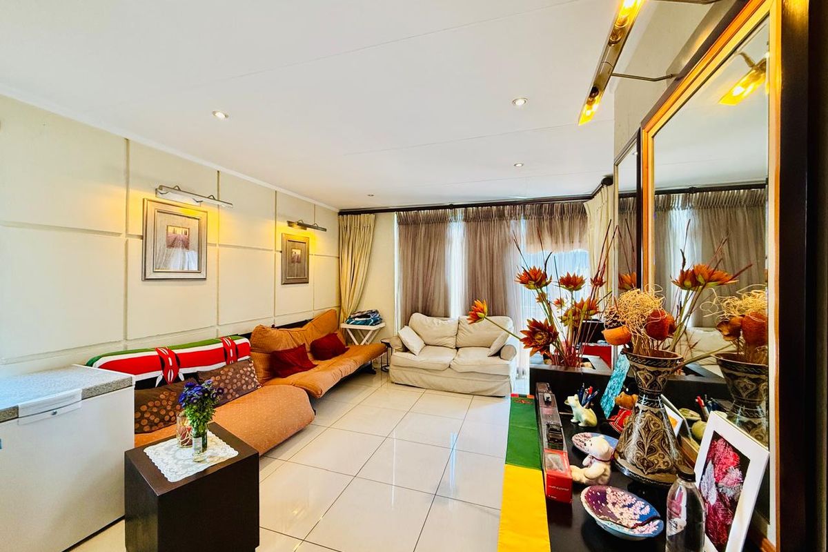 A living room featuring large format floor tiles, recessed downlighting, and wall-mounted accent lighting, providing a bright and functional living space.