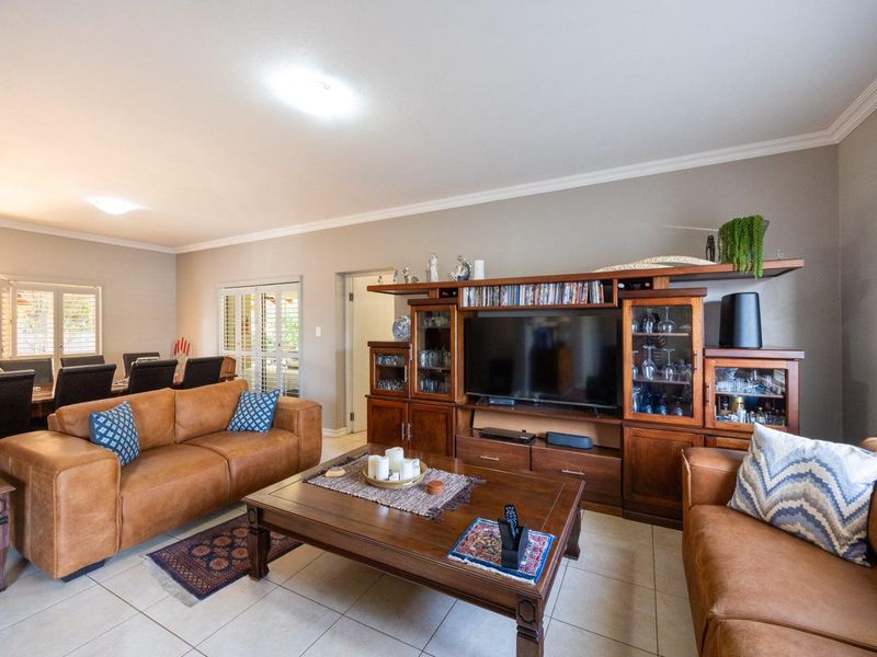 Spacious open-plan living and dining area featuring neutral wall tones, tiled flooring, and classic ceiling cornicing, providing a versatile layout for family living.