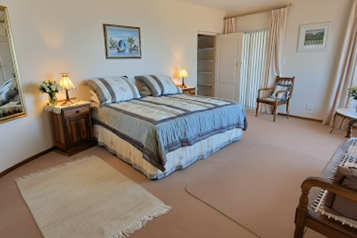 A spacious bedroom featuring neutral carpeting, large windows with vertical blinds, and a built-in closet with shelving.