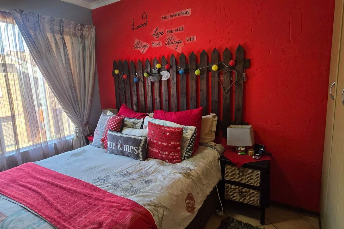 A bedroom featuring tiled flooring and a built-in wardrobe, currently styled with a bold red accent wall.