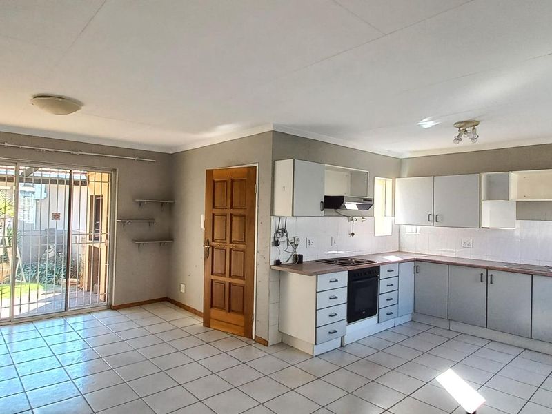 Open-plan living and kitchen area featuring tiled floors, built-in cabinetry, and a sliding glass door providing access to the rear garden.