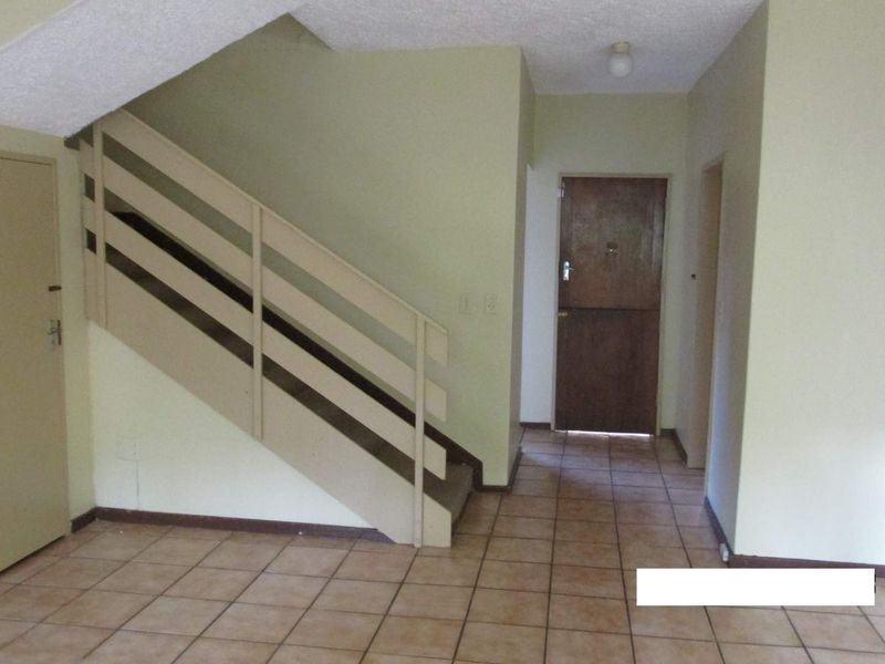 An empty entrance hall featuring tiled flooring and a staircase, providing a functional and neutral space for the home's main entry point.