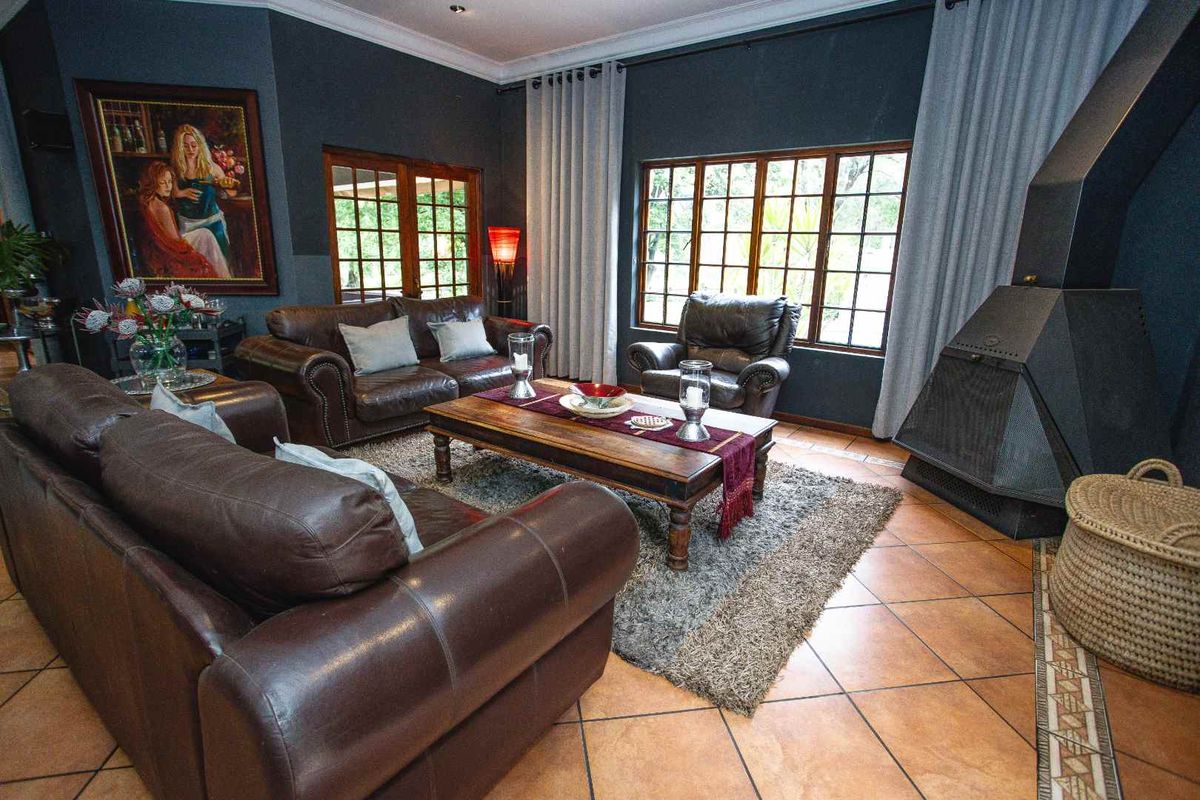 A cozy living room featuring a prominent freestanding fireplace, tiled flooring, and large windows that provide ample natural light.