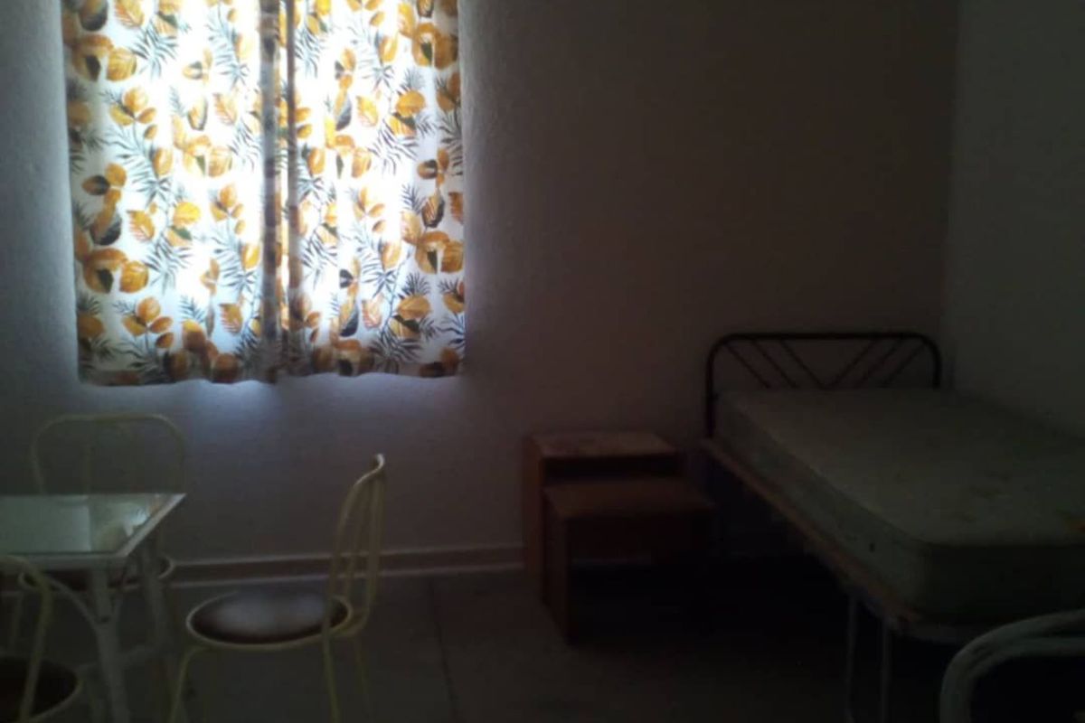 A simple bedroom featuring a window with curtains and basic interior finishes, suitable for a guest room or secondary sleeping area.