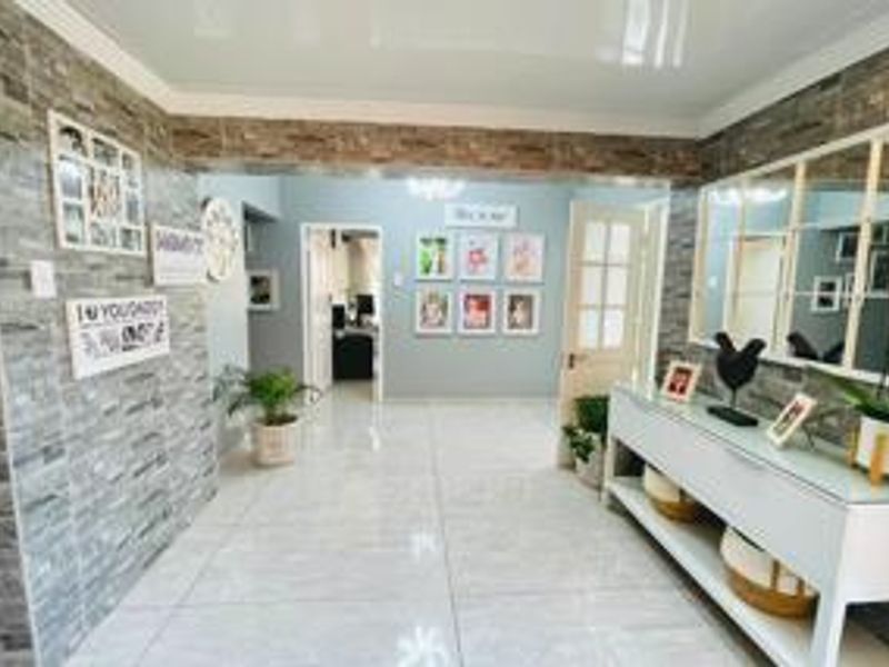 A spacious, well-lit hallway featuring polished tile flooring and a decorative stone-cladding feature wall, providing a welcoming entrance to the home.