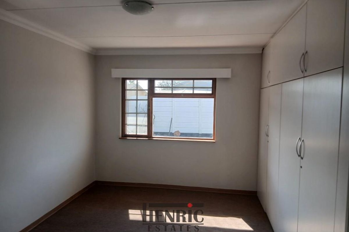 A clean, empty bedroom featuring neutral walls, carpeted flooring, and extensive built-in cupboard storage.