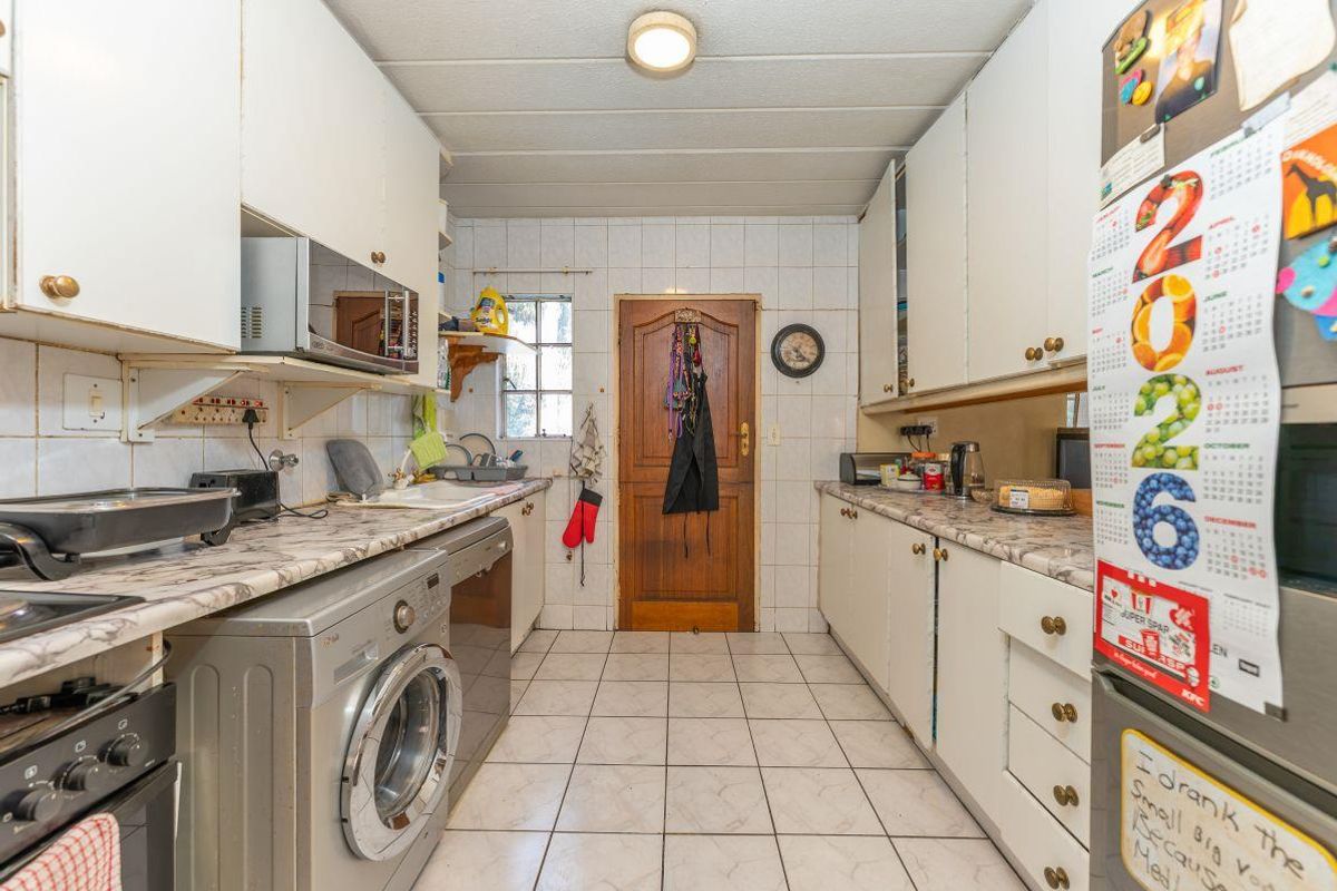 A functional kitchen featuring laminate countertops, tiled flooring, and ample built-in cabinetry, providing a practical workspace with direct access to an exterior door.