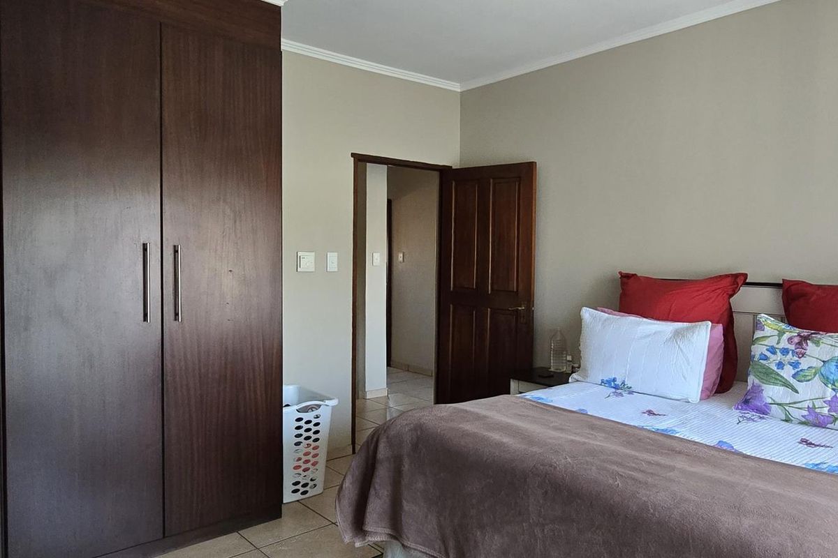 A well-maintained bedroom featuring built-in dark wood cabinetry and tiled flooring, providing a functional and comfortable living space.