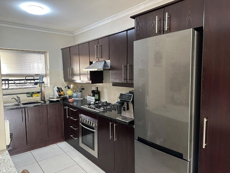 A functional kitchen featuring dark wood cabinetry, granite countertops, a gas hob, built-in oven, and tiled flooring.