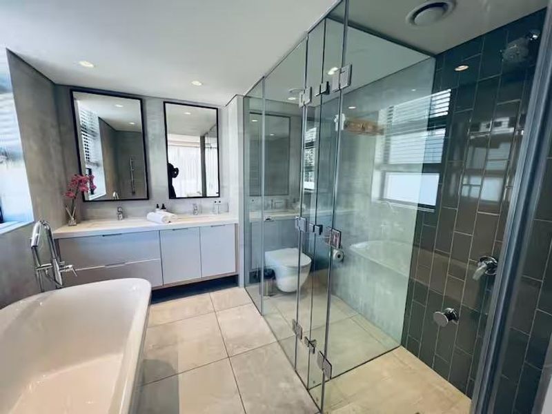 Modern bathroom featuring a freestanding bathtub, double vanity, and a spacious glass-enclosed shower with contemporary tile finishes.