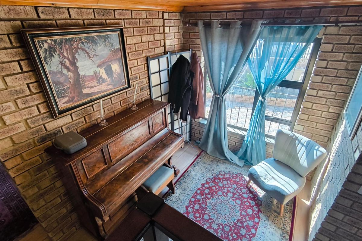 A cozy living area featuring exposed brick walls, a timber ceiling, and a large window that allows for natural light.