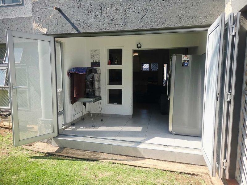 A covered patio area featuring tiled flooring and bi-fold doors, providing a seamless transition between the indoor living space and the garden.