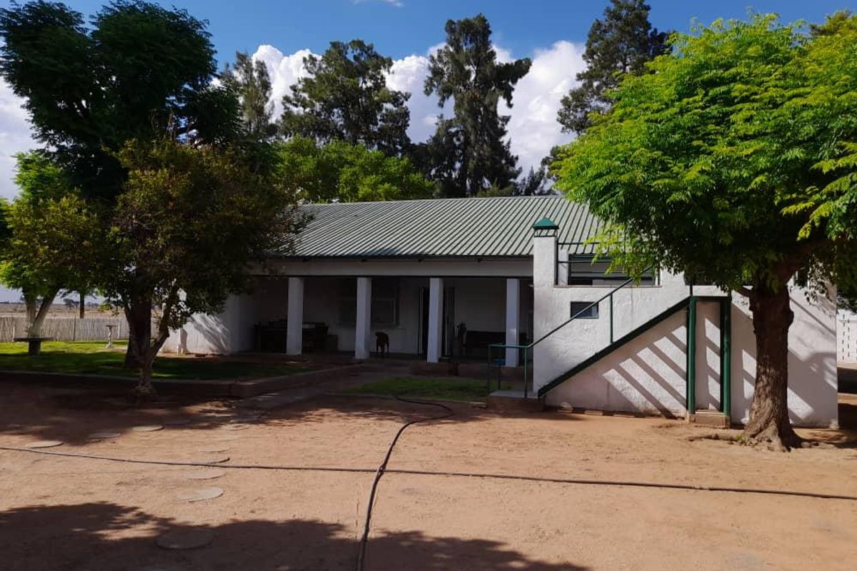 A view of the farm property featuring a covered patio, metal roof, and external staircase leading to an upper level.