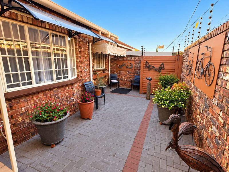 A well-maintained paved rear courtyard featuring facebrick walls, secure electric fencing, and a protective awning over the window area.