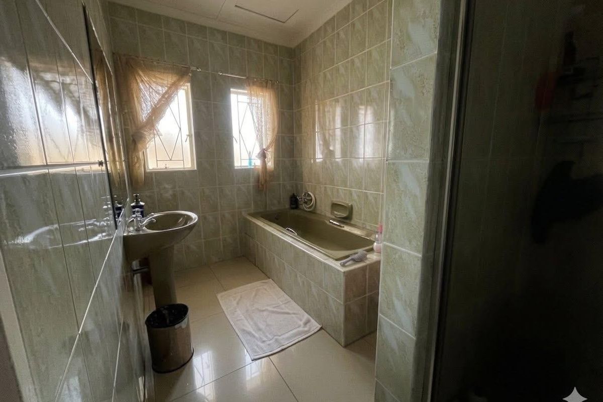 A functional bathroom featuring a built-in bathtub, pedestal basin, and full-height ceramic wall tiling.