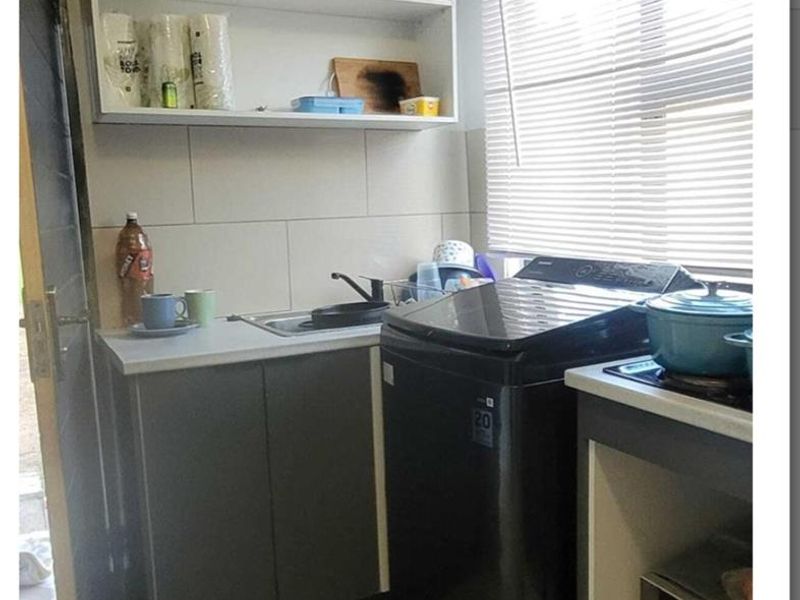 Compact scullery area featuring built-in cabinetry, a stainless steel sink, tiled backsplash, and dedicated space for laundry appliances.