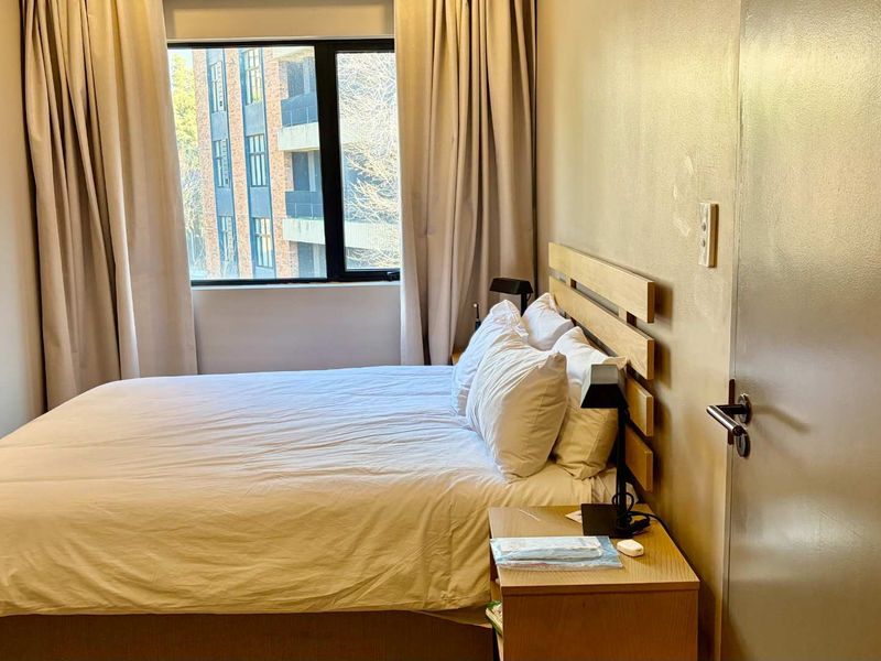 A compact bedroom featuring a window with curtains and a standard door, providing a functional sleeping space.