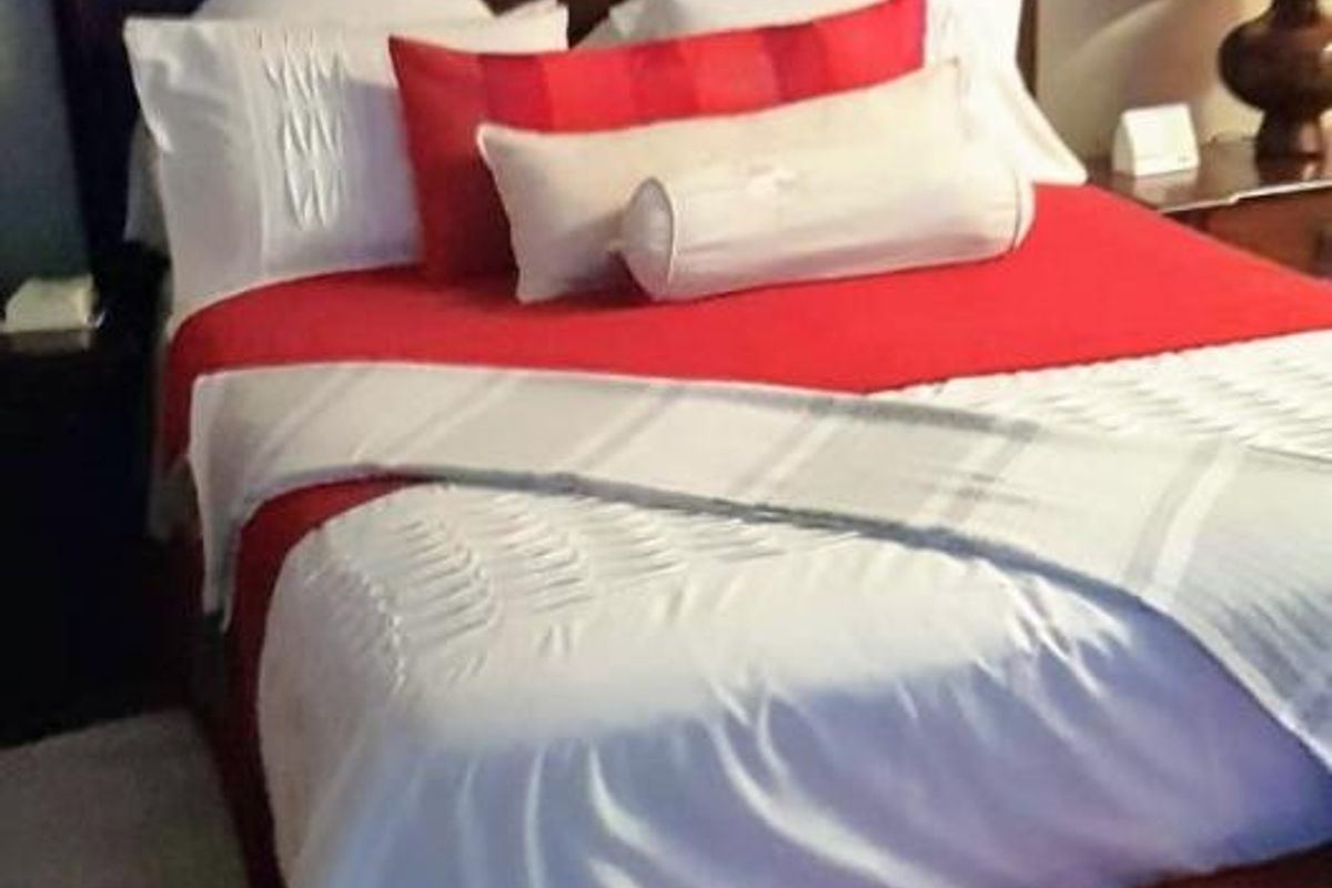 A bedroom featuring hardwood flooring and a dark wood headboard.