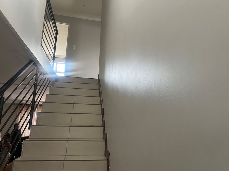 A staircase featuring tiled steps and a modern metal balustrade leading to an upper level landing.
