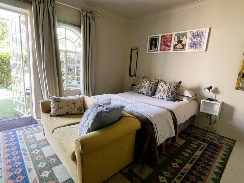 A cozy bedroom featuring french doors that open to a garden area, allowing for natural light and easy outdoor access.