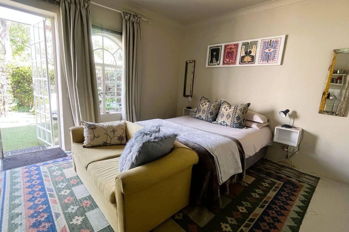 A cozy bedroom featuring french doors that open to a garden area, allowing for natural light and easy outdoor access.