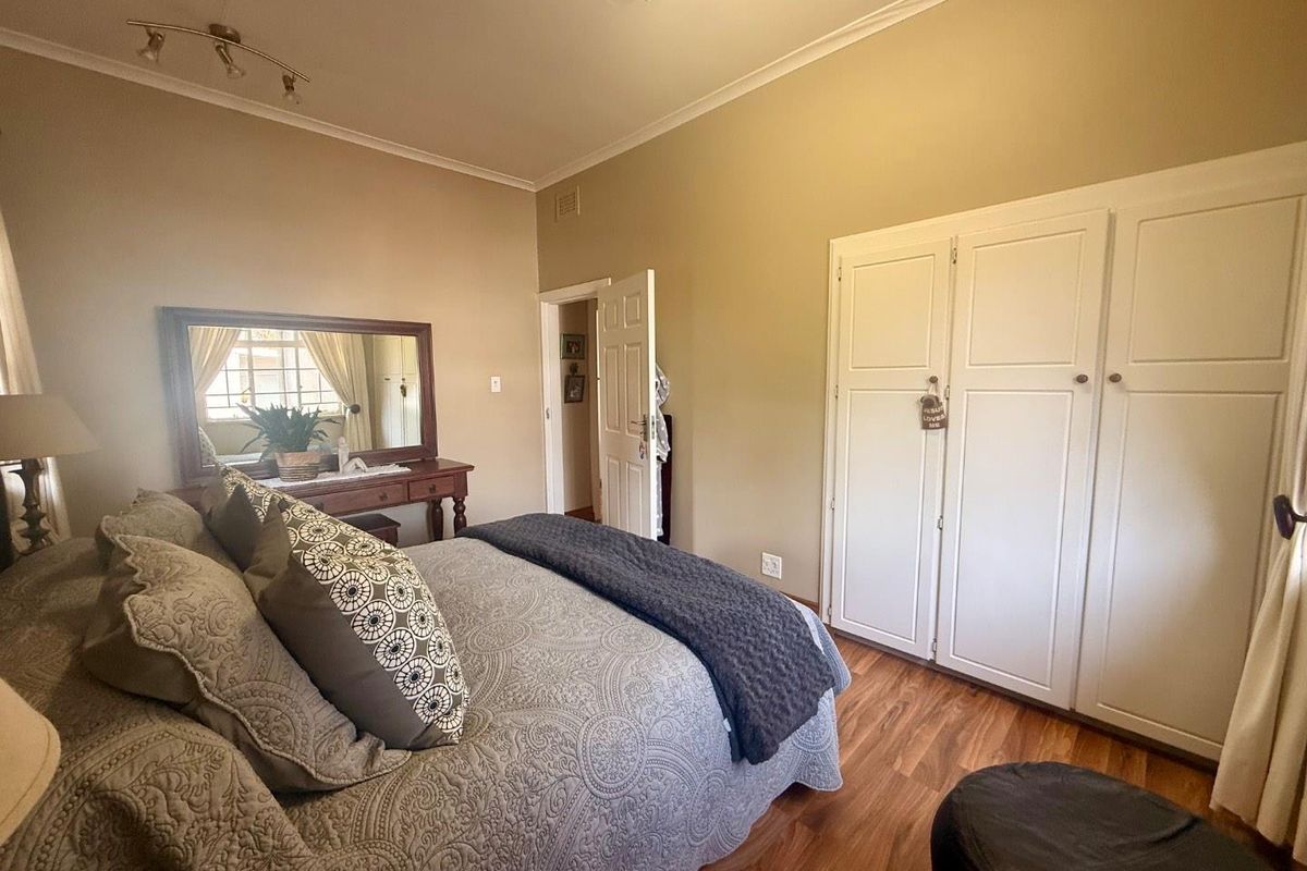 A well-maintained bedroom featuring built-in wardrobes, laminate flooring, and neutral wall tones, providing a comfortable and functional living space.