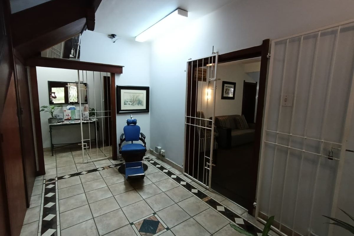 An entry area featuring tiled flooring, security gates, and a staircase, providing access to adjacent rooms within the mixed-use property.