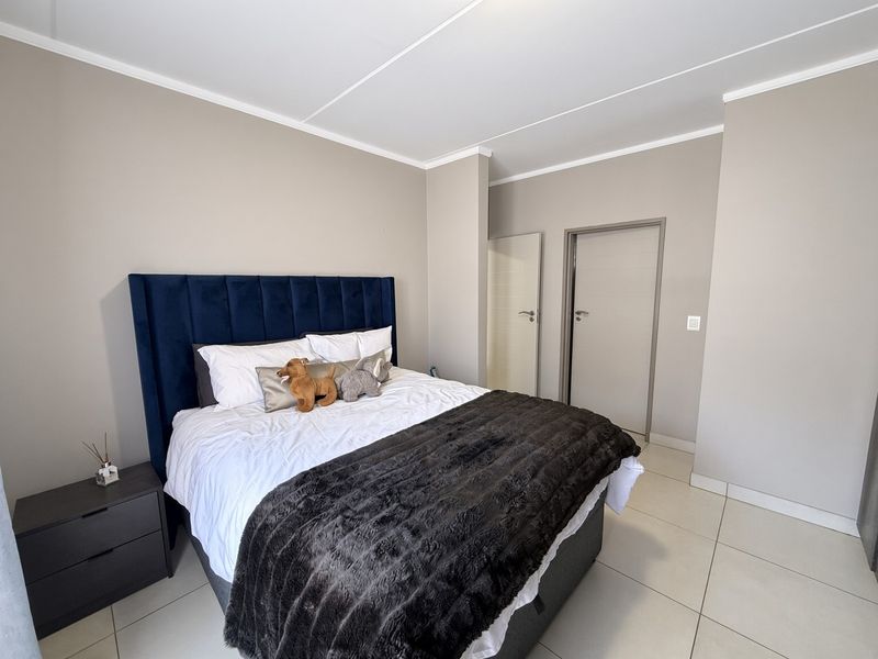 A well-maintained bedroom featuring neutral wall tones, tiled flooring, and clean architectural lines, providing a comfortable and modern living space.