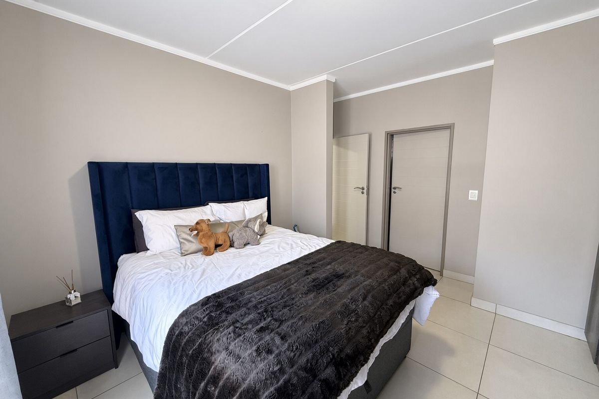 A well-maintained bedroom featuring neutral wall tones, tiled flooring, and clean architectural lines, providing a comfortable and modern living space.