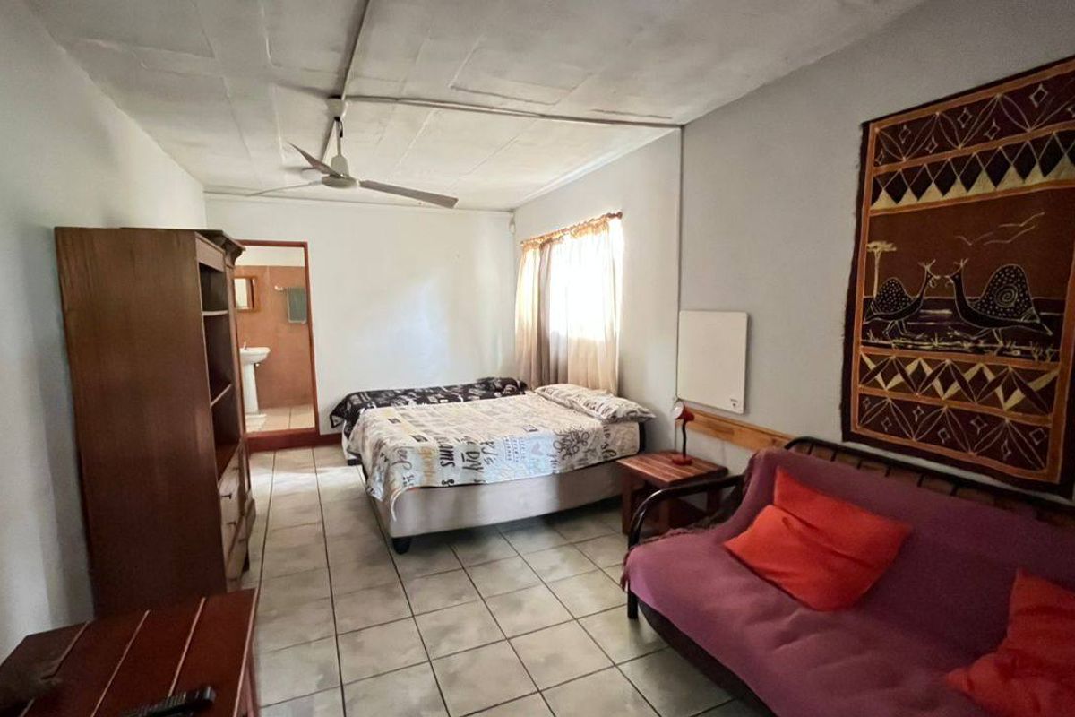 A bedroom featuring tiled flooring, a ceiling fan, and an en-suite bathroom access point.