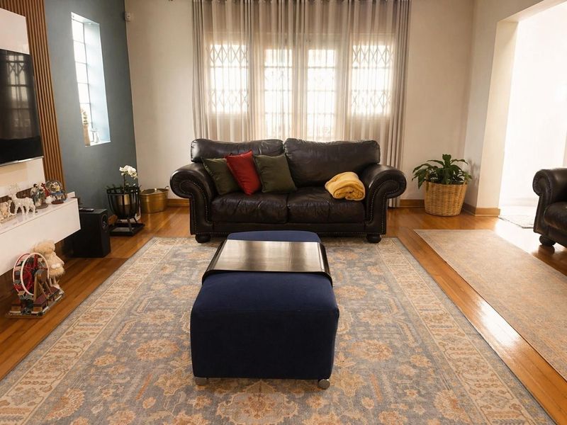 A comfortable living room featuring polished hardwood flooring, a feature slatted wood wall, and a built-in media console with natural light from large windows.