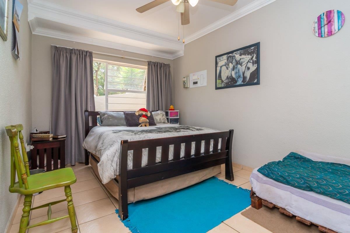 A bedroom featuring tiled flooring, crown molding, and a ceiling fan, providing a functional living space with natural light from the window.
