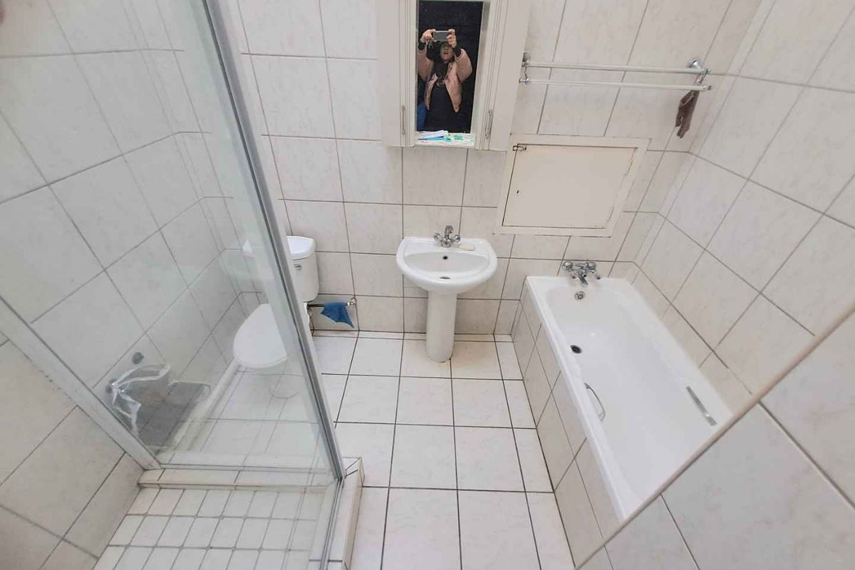 A functional bathroom featuring a pedestal basin, bathtub, and separate glass shower enclosure with full-height wall tiling.
