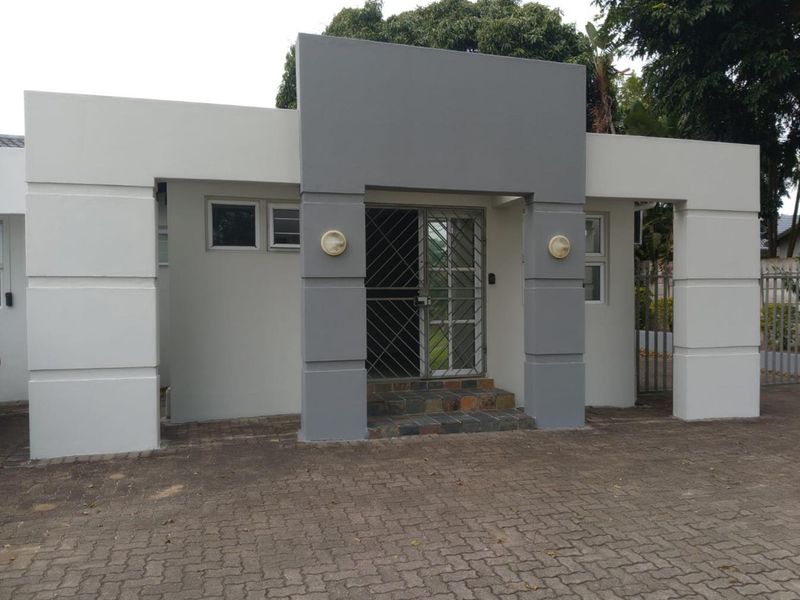 Modern office entrance featuring a paved driveway, stone-tiled steps, and a secure metal gate, presenting a clean and professional exterior facade.