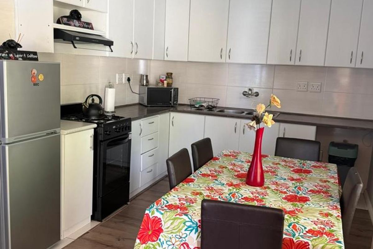 A functional kitchen featuring white cabinetry, laminate countertops, a tiled backsplash, and a freestanding stove, providing a practical layout for daily cooking and dining.