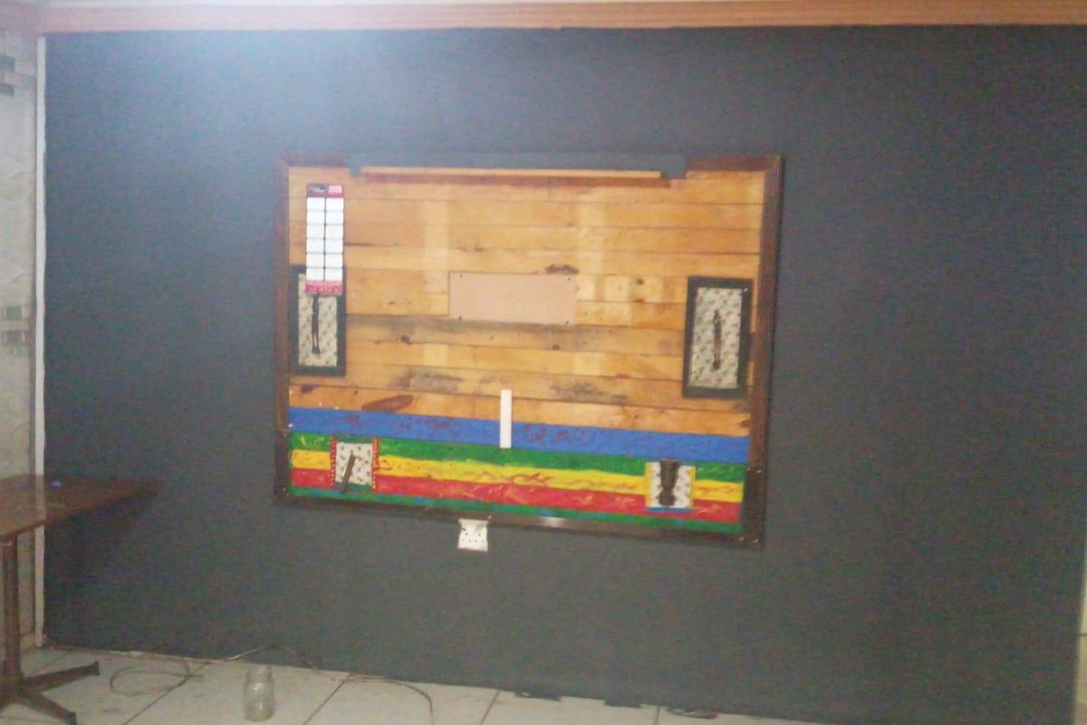 An interior space featuring a dark painted wall with a decorative wooden panel installation and tiled flooring.