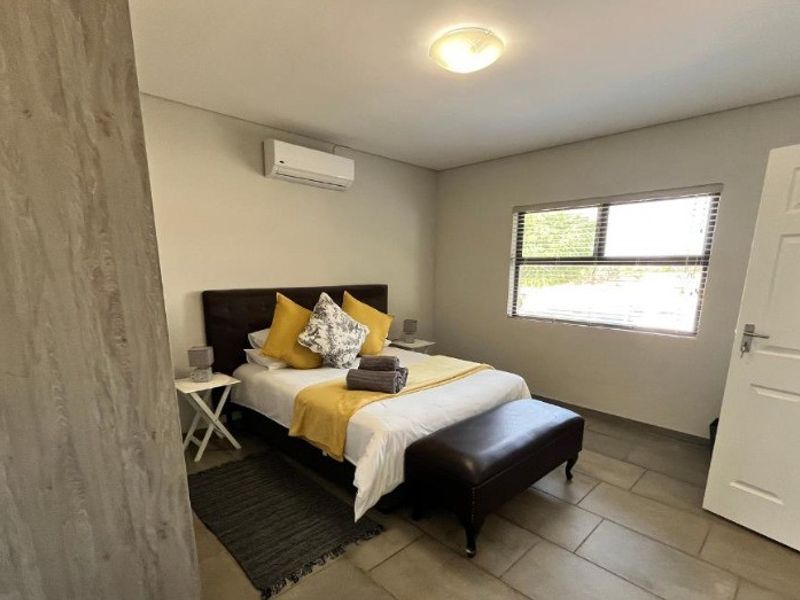 A well-maintained bedroom featuring tiled flooring, a split-system air conditioner, and a built-in cupboard, offering a comfortable and functional living space.